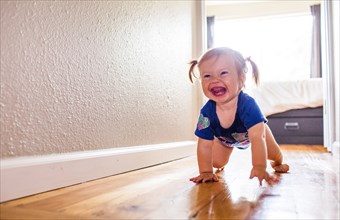 Caucasian baby girl crawling in hallway