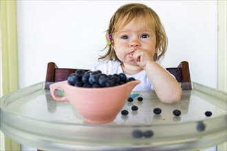 Caucasian baby girl eating blueberries