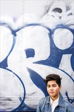 Asian woman standing at graffiti wall