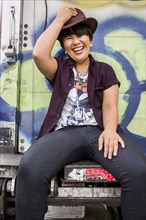 Asian woman sitting on graffiti truck