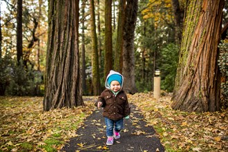 Caucasian baby girl walking in autumn park