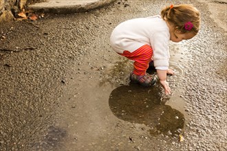 Caucasian baby girl playing in puddle