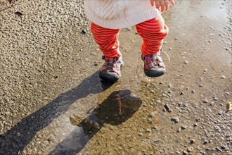 Caucasian baby girl walking in puddle