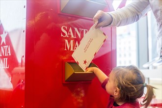 Caucasian mother and daughter mailing letter to Santa