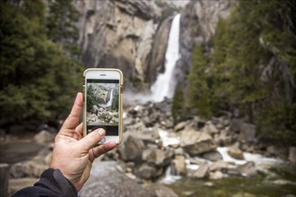 Man photographing waterfall in Yosemite National Park