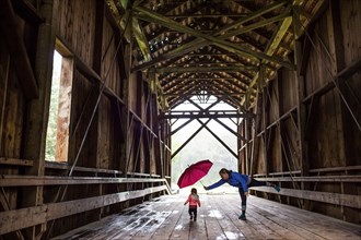 Caucasian mother and baby daughter on covered bridge