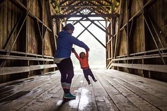 Caucasian mother and baby daughter on covered bridge