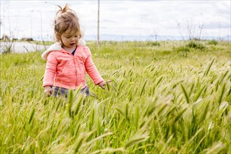 Caucasian baby girl playing in field