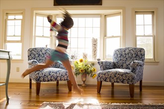 Carefree Caucasian girl running and jumping in livingroom