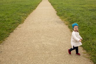 Smiling Caucasian baby girl walking on path