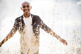 Smiling gay Black man standing in tall grass