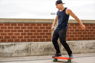 Caucasian man skateboarding near brick wall