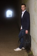 Caucasian man leaning on wall in tunnel