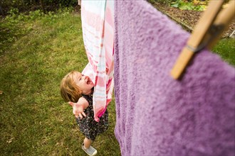 Caucasian baby girl playing with towels on clothesline