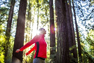Woman stretching arms in sunny forest