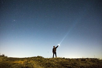 Caucasian man pointing flashlight at night sky