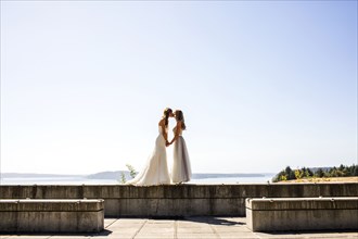 Caucasian brides kissing at waterfront