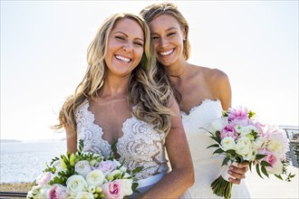 Smiling Caucasian brides holding bouquets