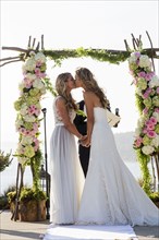 Caucasian brides kissing at wedding ceremony