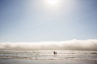 Caucasian mother and son wading in ocean waves at beach