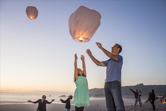 Caucasian father and daughter flying lantern balloon at beach