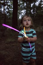 Caucasian girl holding glow sticks in forest