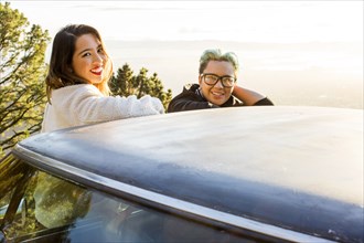 Portrait of smiling Asian women leaning on car