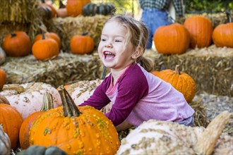 Smiling Caucasian girl playing in pumpkin patch