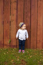 Caucasian girl standing near wooden fence