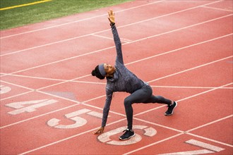 Black woman stretching on track starting line