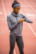 Black woman checking smart watch on track