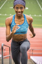 Smiling Black woman running on bleachers