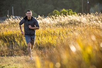 Smiling Mixed Race man running in field