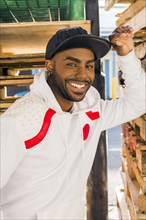 Smiling Black man leaning on wooden pallets