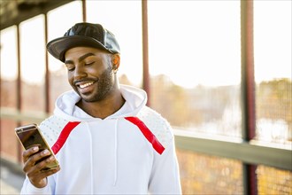 Smiling Black man texting on cell phone