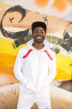 Smiling Black man leaning on graffiti wall