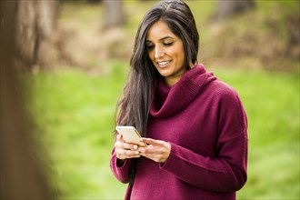 Smiling Indian woman texting on cell phone