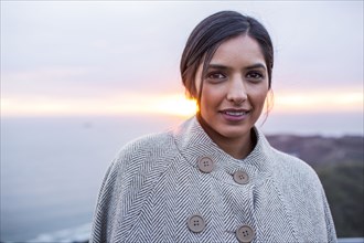 Portrait of serious Indian woman near ocean at sunset