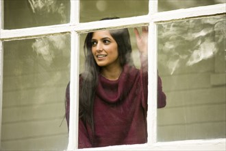 Smiling Indian woman leaning on window