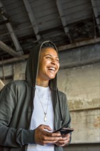 Laughing androgynous Mixed Race woman texting on cell phone