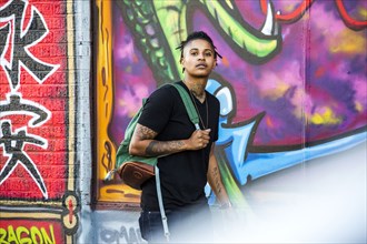 Portrait of androgynous Mixed Race woman near graffiti wall