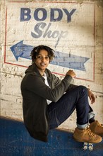 Portrait of androgynous Mixed Race woman sitting in body shop