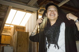 Androgynous Asian man holding scarf on head