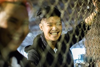 Androgynous Asian man and woman leaning on fence