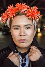 Portrait of serious androgynous Asian woman with flowers in hair