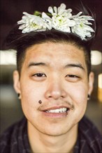 Portrait of androgynous Asian man with flowers in hair