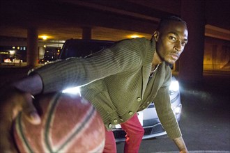 Headlights shining on Black man playing basketball