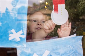 Caucasian girl pressing snowman decoration on window