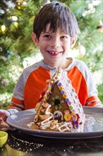 Mixed Race boy with gingerbread house on plate