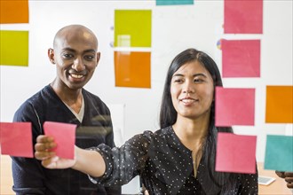 Woman and man reading adhesive notes in office